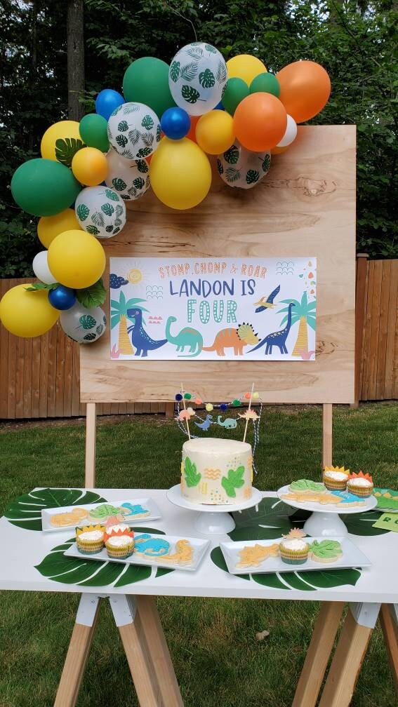 Custom Dinosaur Birthday Banner and balloon garland dessert table set up at a dino party