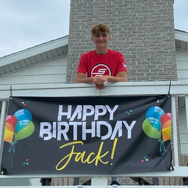 birthday banner hanging from deck with smiling boy