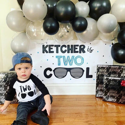 Two Cool birthday banner with sunglasses and balloon garland pictured with birthday boy