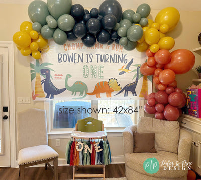 dinosaur birthday banner with balloon garland in orange, golden yellow, sage green and navy blue