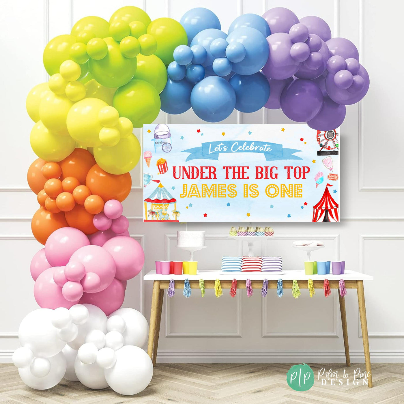 under the big top banner with circus and carnival clipart in front of rainbow balloon garland