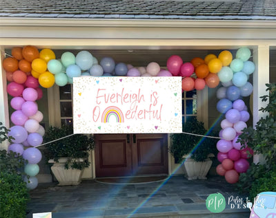 rainbow birthday banner in front of house with balloon garland