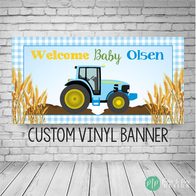Blue tractor baby shower banner with blue gingham border, golden wheat accents, and Welcome Baby text